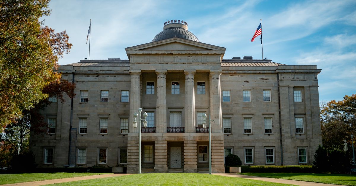 Front view of the historic North Carolina State Capitol in Raleigh, showcasing neoclassical architecture under a blue sky.